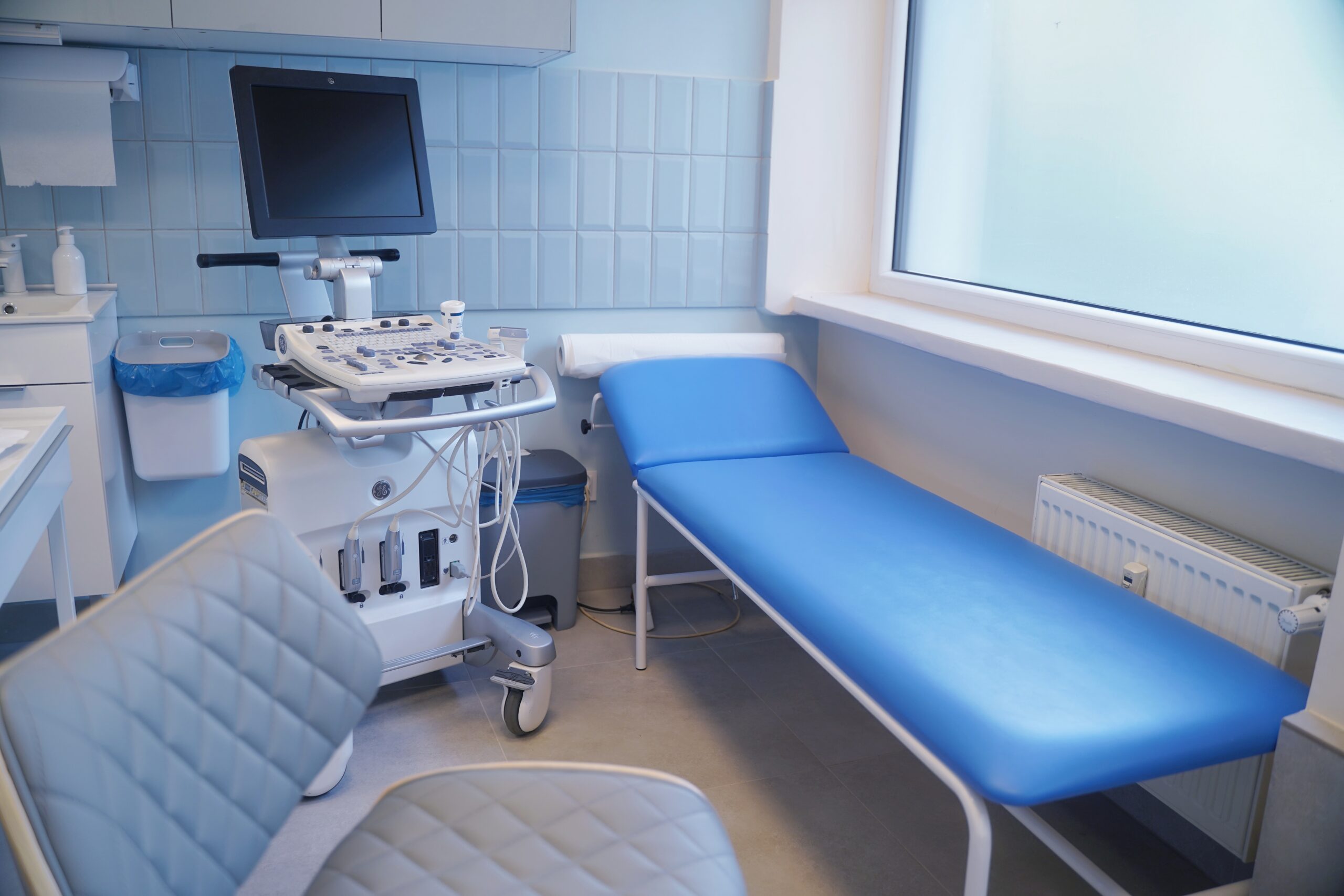 Gabinet diagnostyki USG z niebieską kozetką i aparatem ultrasonograficznym